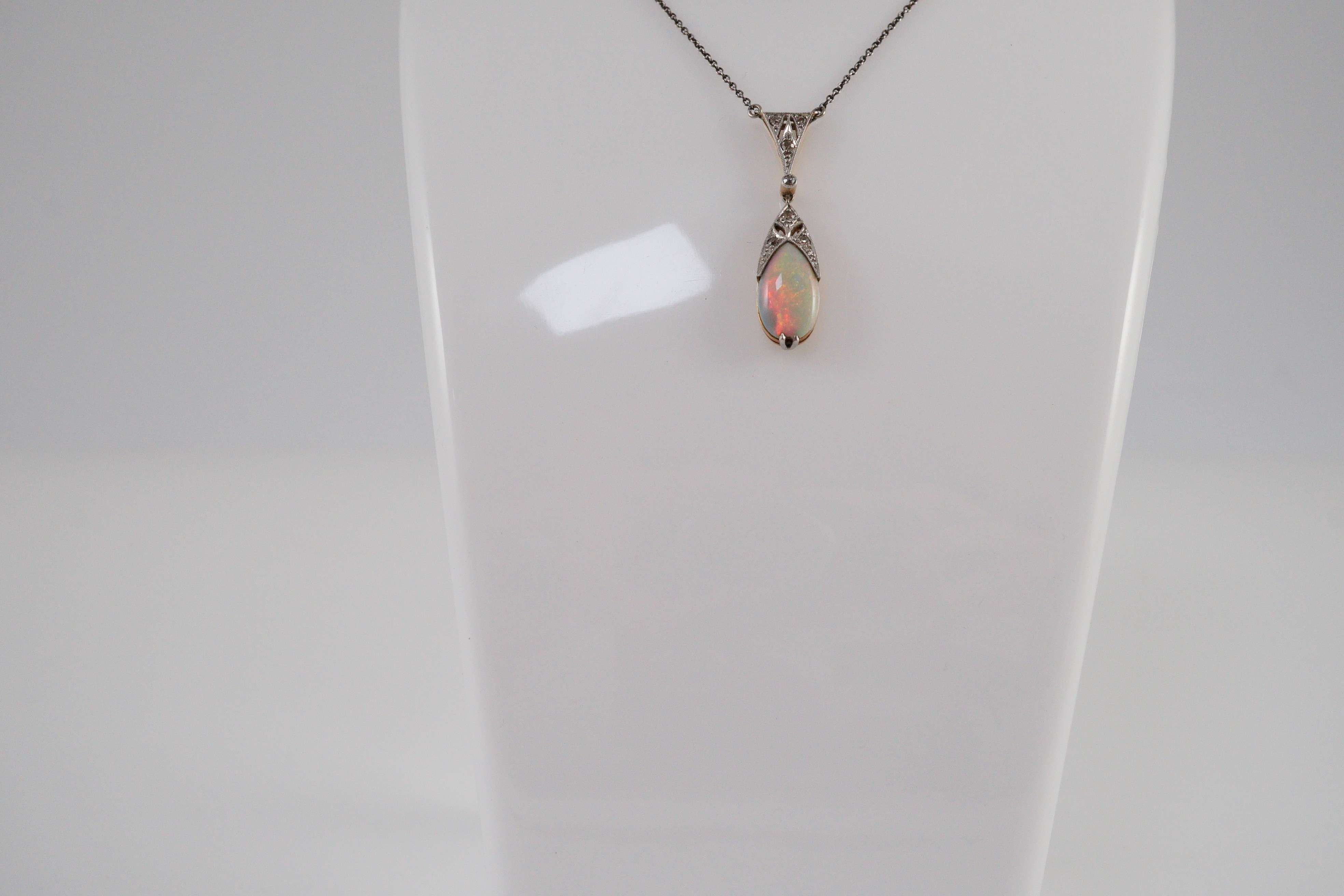 A 1920's gold and platinum, white opal and millegrain set diamond cluster pear shaped drop pendant necklace